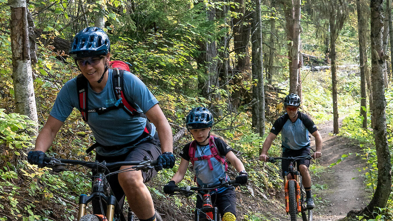 A family riding mountain bikes on a trail.